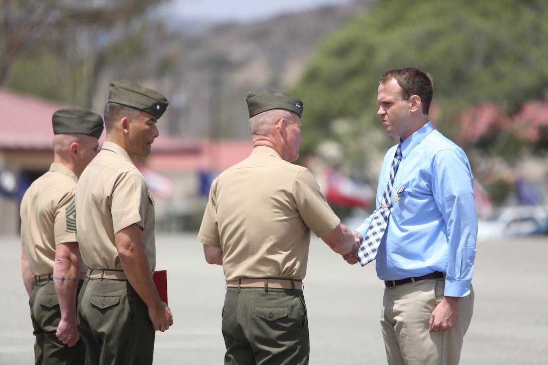 Major Gen. Lawrence Nicholson, commanding general, 1st Marine Division, congratulates Sgt. Matthew T. Woodall, former squad leader, Bravo Company, 1st Battalion, 5th Marine Regiment, after awarding him the Silver Star Medal during an award ceremony at the Camp San Mateo parade deck here, Aug. 2, 2013. Woodall, a native of Paducah, Ky., earned the nation's third highest military award for valor for his actions in Helmand province, Afghanistan, in support of Operation Enduring Freedom. A platoon-sized enemy force attacked Woodall and his Marines from several fortified positions during a security patrol mission in the Sangin district of Helmand, July 10 through 11, 2011. His daring actions ultimately defeated the enemy attack, killing four insurgents and wounding many others.