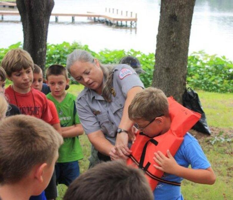Renea Guin, U.S. Army Corps of Engineers Natural Resource Specialist/ Ranger teaches proper wear of lifejacket.

The camp is geared towards youth aged 5-13 years, with approximately 100 youth having enrolled this year. Through this partnership, the educational camp includes a Fun Day at Arc Isle, a public park at Lake Hamilton. This Fun Day at Arc Isle is one of the educational field trips which gives the youth the opportunity to swim in Lake Hamilton.
