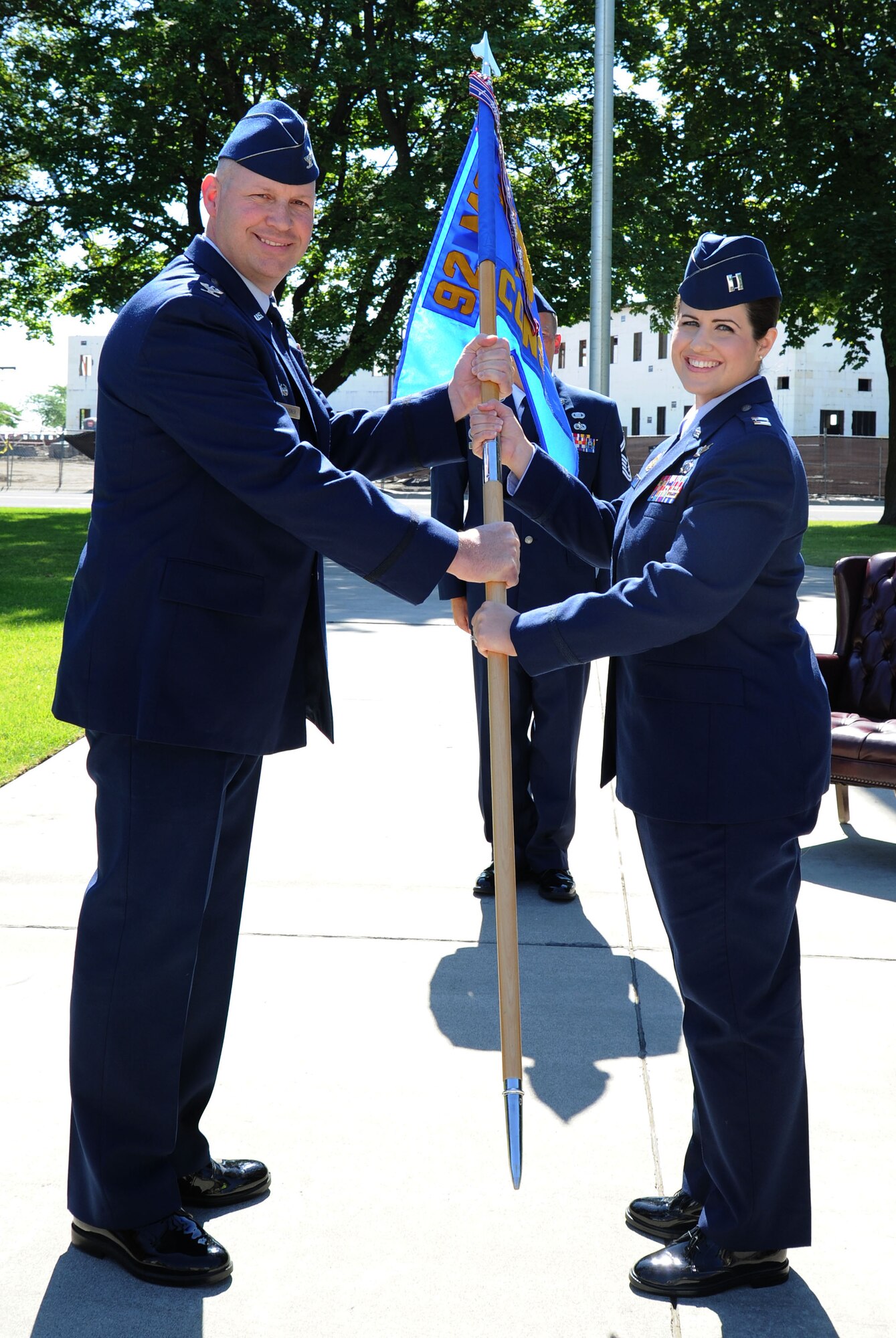 Col. Konrad Klausner, 92nd Mission Support Group commander, hands the guidon to Capt. Kelly Gerlach, 92nd Contracting Squadron commander, during the 92nd CONS Change of Command ceremony at Fairchild Air Force Base, Wash., Aug. 5, 2013. The change of command ceremony is a tradition that represents a formal transfer of authority and responsibility. (U.S. Air Force photo by Airman 1st Class Janelle Patiño/Released)