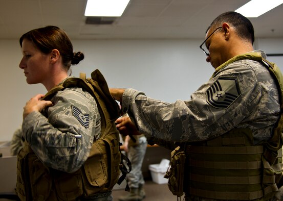 U.S. Air Force Reserve Master Sgt. Rodolfo Castro, broadcast journalist, 4th Combat Camera Squadron, adjusts an improved outer tactical vest for Tech. Sgt. Christine Jones, photojournalist, 4th CTCS, during annual tour at March Air Reserve Base, Calif., July 27, 2013. The squadron took advantage of annual tour to learn and practice night vision operations, military operations on urban terrain, wear and use of tactical gear, battlefield forensics, and more. The 4th CTCS is the only combat camera squadron in the U.S. Air Force Reserve. (U.S. Air Force photo by Staff Sgt. Carolyn Herrick) 