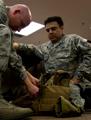 U.S. Air Force Reserve Senior Airman Kevin Mitterholzer and Tech. Sgt. Francisco Govea, 4th Combat Camera Squadron, make adjustments to an improved outer tactical vest during annual tour at March Air Reserve Base, Calif., July 27, 2013. The squadron took advantage of annual tour to learn and practice night vision operations, military operations on urban terrain, wear and use of tactical gear, battlefield forensics, and more. The 4th CTCS is the only combat camera squadron in the U.S. Air Force Reserve. (U.S. Air Force photo by Staff Sgt. Carolyn Herrick) 