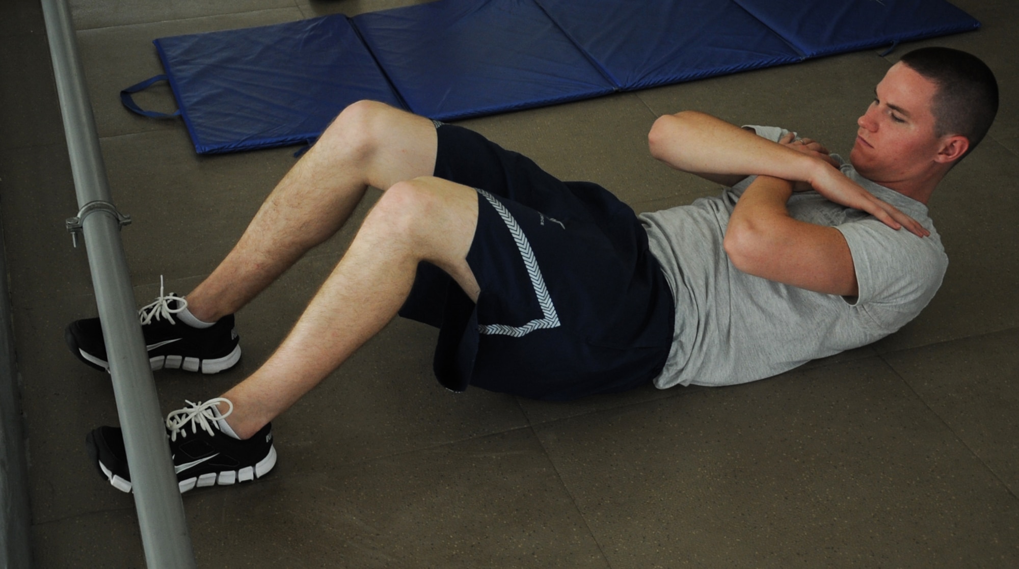 Senior Airman Dustin Rottinghaus, 26th Operational Weather Squadron weather forecaster, demonstrates a proper sit-up during a physical fitness test on Barksdale Air Force Base, La., Aug. 5, 2013. Each portion of the test is demonstrated to ensure testers perform push-ups and sit-ups correctly. (U.S. Air Force photo/Senior Airman Sean Martin)
