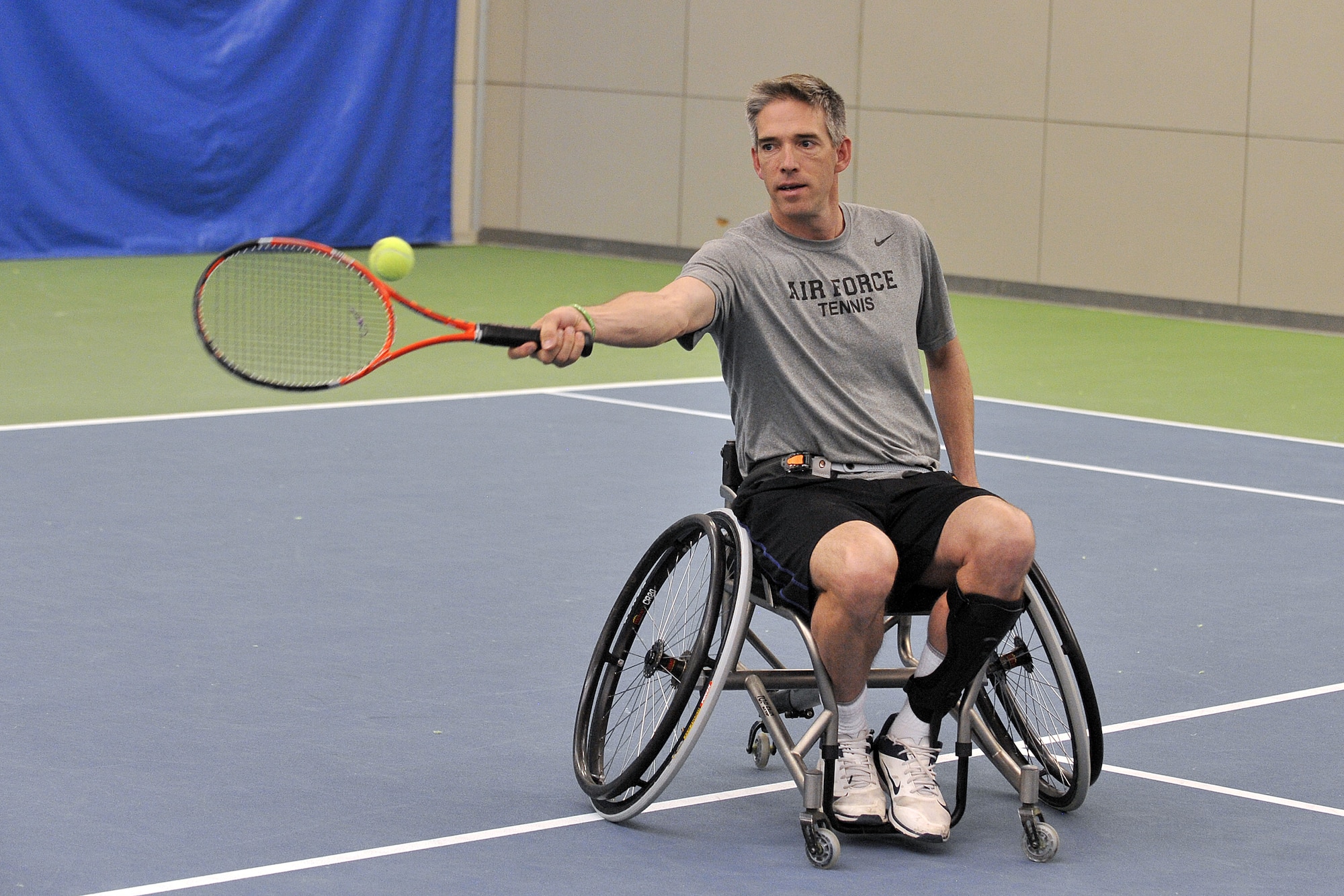 Lt. Col. Dan Oosterhous maneuvers on the court in a wheelchair to meet a forehand shot during a May 14, 2013 Warrior Games tennis clinic here.  (U.S. Air Force photo/Raymond McCoy)
