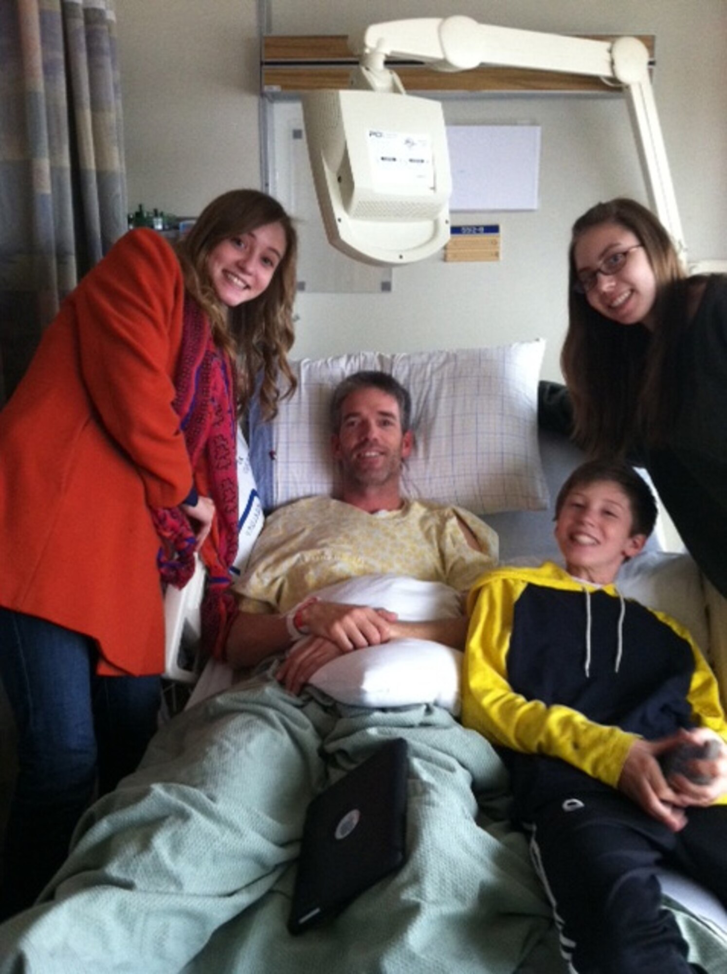 Lt. Col. Dan Oosterhous recovers in Memorial Hospital’s Intensive Care Unit March 24 with his children, Emma (left), Andrew and Anna (right), following his second stroke. (U.S. Air Force courtesy photo)
