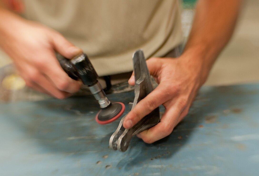 Airman 1st Class Tyler Jones, 28th Maintenance Squadron aircraft metals technician, smoothes an aircraft nose bracket with a sanding disc at Ellsworth Air Force Base, S.D., July 30, 2013. Aircraft metals technicians are certified in metal repair, fabrication, metal composition, weld specifications, metal tempering, forging, mechanical drawings and the use of precision measuring devices, etc. (U.S. Air Force photo by Airman 1st Class Zachary Hada/Released)