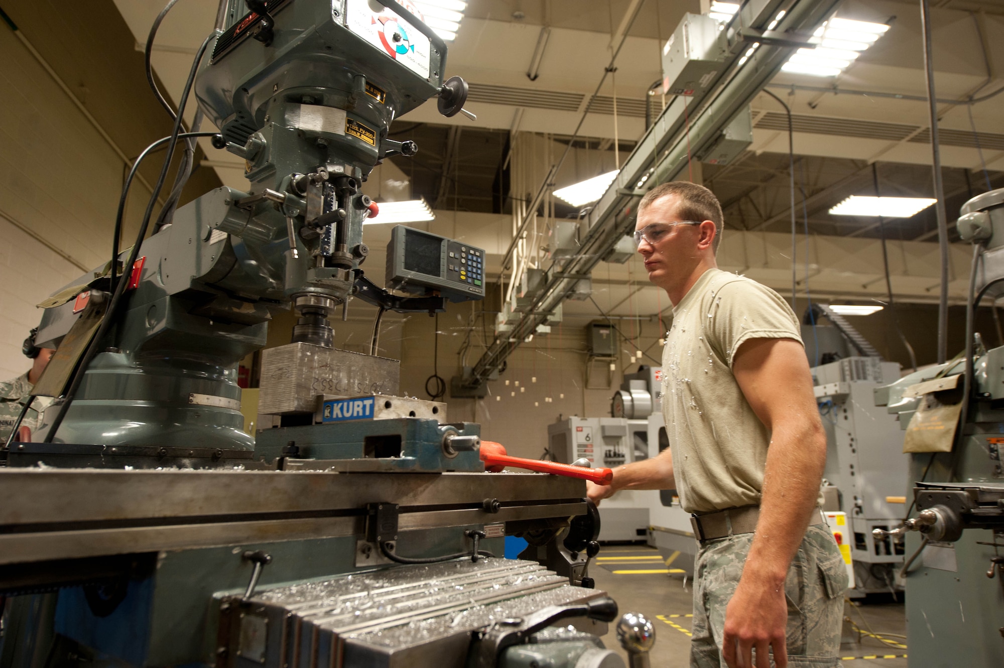 Airman 1st Class Tyler Jones, 28th Maintenance Squadron aircraft metals technician, uses a grinder to shape an aircraft nose bracket from a metal block at Ellsworth Air Force Base, S.D., July 30, 2013. Aircraft metals technicians are trained and certified on several methods to repair and fabricate a variety of parts for Ellsworth’s 28 B-1 bombers. (U.S. Air Force photo by Airman 1st Class Zachary Hada/Released)