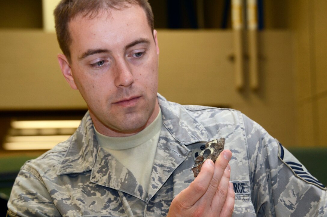Master Sgt. Jason A. Mellor an explosive ordnance disposal specialist from the 94th Explosive Ordnance Disposal Flight, Dobbins Air Reserve Base, Ga., examines a fragment of a civil war era cannon ball at the base Aug 2. The cannon ball was detonated and disposed of by the Dobbins EOD team after being discovered near Centennial Park, downtown Atlanta July 18. (U.S. Air Force photo/Don Peek)