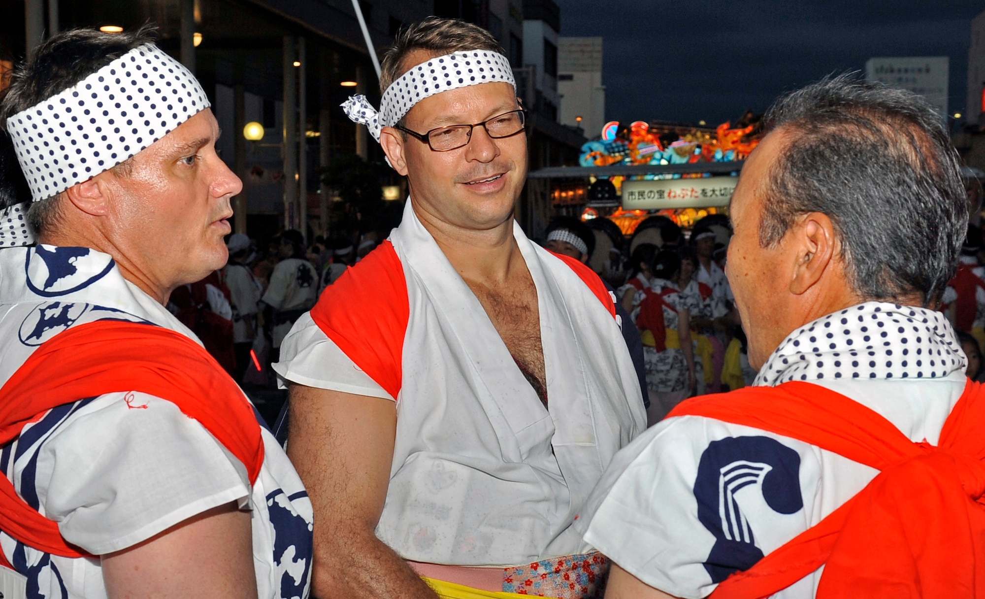 U.S. Air Force Col. Matthew Dana, left, 35th Fighter Wing vice commander, and Col. Stephen Williams, 35 FW commander, talk to Chikao Yamamoto, Japan-America Air Force Goodwill Association Misawa Branch chief of administration,  before the start of the Aomori Nebuta Festival parade at Aomori City, Japan, Aug. 3, 2013. As the sun goes down, lanterns are illuminated within various floats and are paraded around the city. (U.S. Air Force photo by Airman 1st Class Zachary Kee)