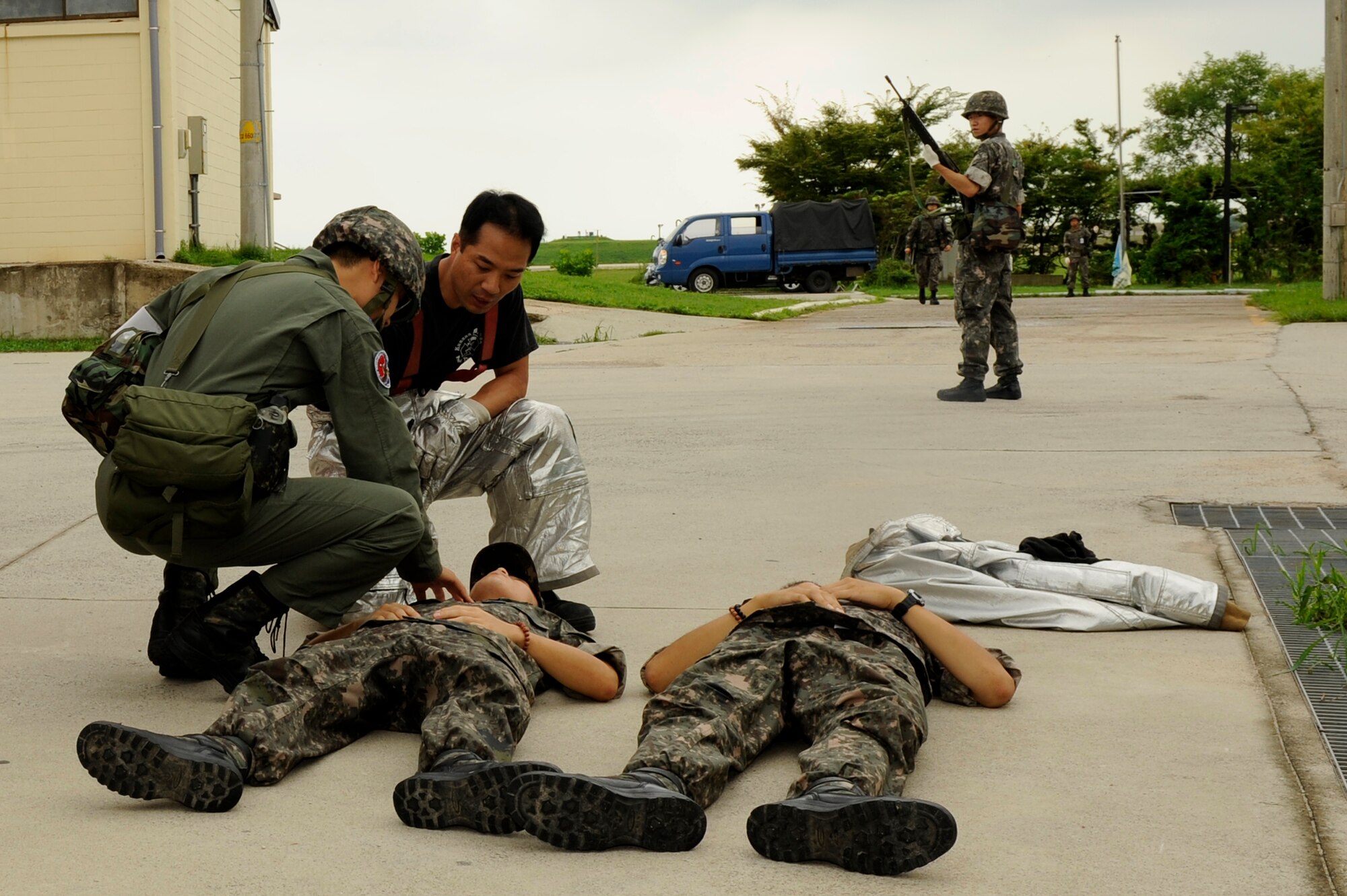 KUNSAN AIR BASE, Republic of Korea – Kyong Min Kim, 8th Civil Engineer Squadron firefighter, middle, and a Republic of Korea air force, 38th Fighter Group medic, provide aid to ROKAF victims during exercise Beverly Midnight 13-3, Aug. 5, 2013. First responders from the U.S. Air Force and ROKAF combined during an electrical fire scenario to test their coordinated response. (U.S. Air Force Photo by Staff Sgt. Tong Duong/Released)