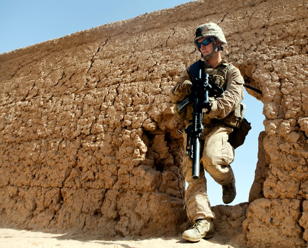 U.S. Marine Corps Cpl. Michael Emerson steps through the wall of an Afghan compound while searching for any evidence of insurgency and weapons during Operation Grizzly IV near Patrol Base Boldak in Helmand province, Afghanistan, July 29, 2013. Emerson is assigned to Fox Company, 2nd Battalion, 2nd Marine Regiment.