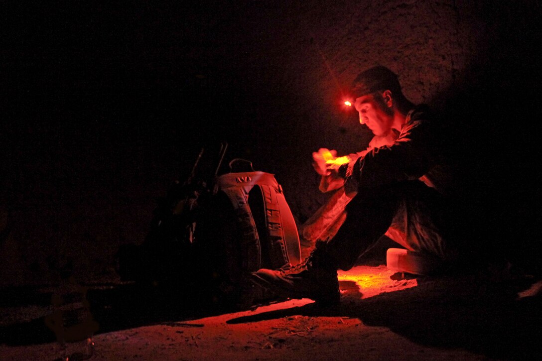 U.S. Marine Corps 1st Lt. Jerry Wells uses a headlamp to eat oatmeal inside an abandoned house before leaving for an early morning patrol in support of Operation Grizzly IV near Patrol Base Boldak in Helmand province, Afghanistan, July 30, 2013. Wells is assigned to Fox Company, 2nd Battalion, 2nd Marine Regiment.