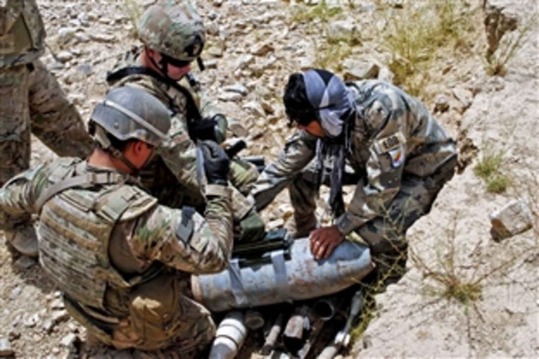 U.S. Air Force Senior Airman Alex Gaunt, left, and U.S. Air Force Staff Sgt. Jason Halgren, center, work with an Afghan border policeman explosive ordnance disposal trainee to prepare explosives for a controlled detonation in the Spin Boldak district in Afghanistan’s Kandahar province, July 28, 2013. Gaunt, an explosive ordnance disposal journeyman, and Halgren, an explosive ordnance disposal craftsman, are assigned to the 466th Air Expeditionary Group.