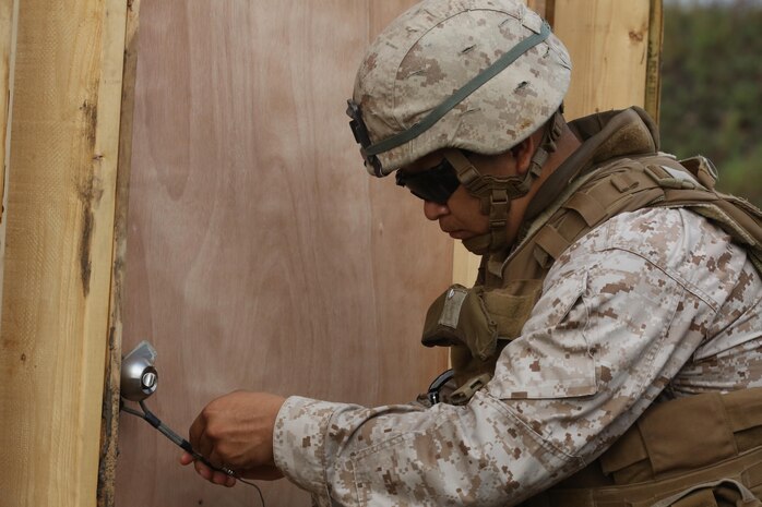 A combat engineer with 8th Engineer Support Battalion, 2nd Marine Logistics Group sets an explosive charge on a doorknob during a field operation aboard Camp Lejeune, N.C., July 29, 2013. The unit joined 2nd Assault Amphibian Battalion, 2nd Marine Division for a training exercise with explosive demolitions for urban and field environments. 