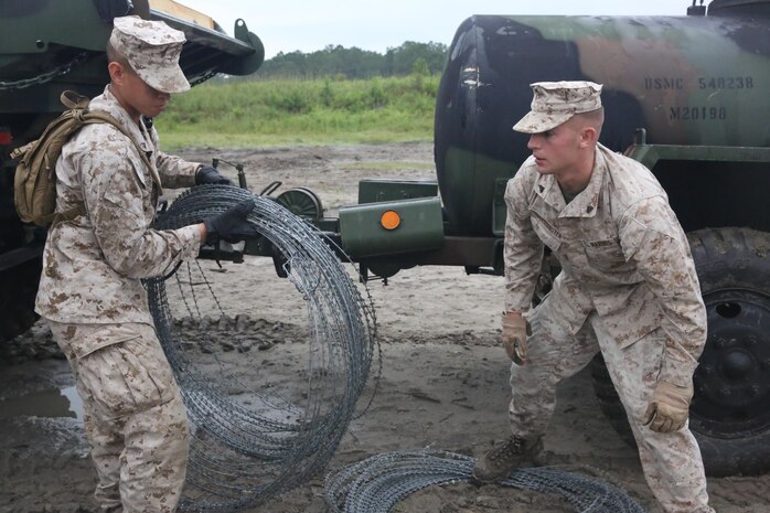 Combat engineers with 8th Engineer Support Battalion, 2nd Marine Logistics Group gather concertina wire to be breached with explosives during a field exercise aboard Camp Lejeune, N.C., July 29, 2013. The engineers trained with Marines from 2nd Assault Amphibian Battalion, 2nd Marine Division on the basics of urban and field demolitions. 