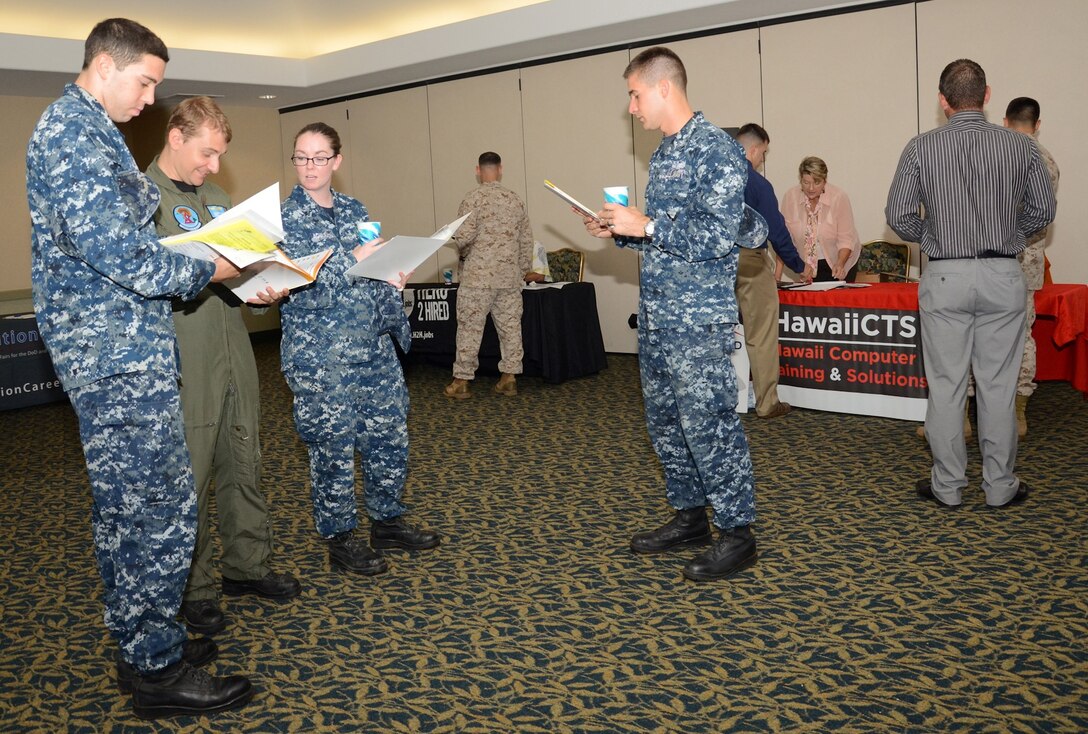 A group of service members browse through a fair program during the Hawaii Defense Tech and Intelligence Career Fair, in the Fairways Ballroom at the Kaneohe Klipper Golf Course, July 30, 2013. Service members, Department of Defense civilians and contractors were invited to this free event. The companies at the fair pertained to professionals in fields including information technology, software engineering, aerospace, logistics, cyber security, project management, network administration and linguistics. For more information, visit http://www.transitioncareers.com, or call the Marine Corps Community Services Transition Readiness Program at 257-7787/7790. (U.S. Marine Corps photo by Kristen Wong)