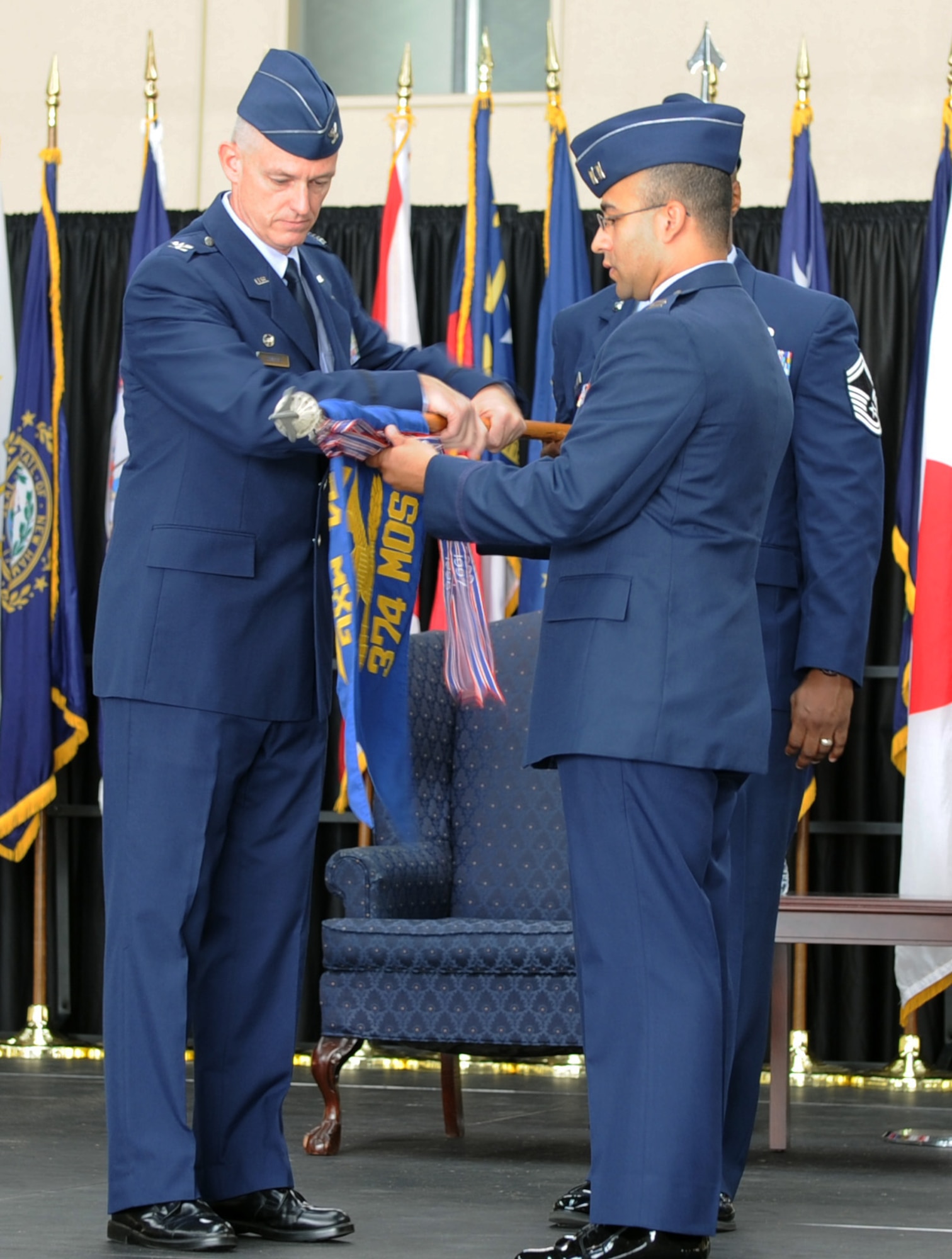 YOKOTA AIR BASE, Japan -- Left, Col. Kevin Sampels, 374th Maintenance Group commander, and Capt. Fernando Rolon, 374th Maintenance Operations Squadron commander, roll the 374 MOS flag during the inactivation ceremony July 31, 2013, at Yokota Air Base, Japan. Airmen in the 374 MOS will remain at Yokota to perform their mission as the 374th Maintenance Operations. (U.S. Air Force photo by Senior Airman Desiree Economides)