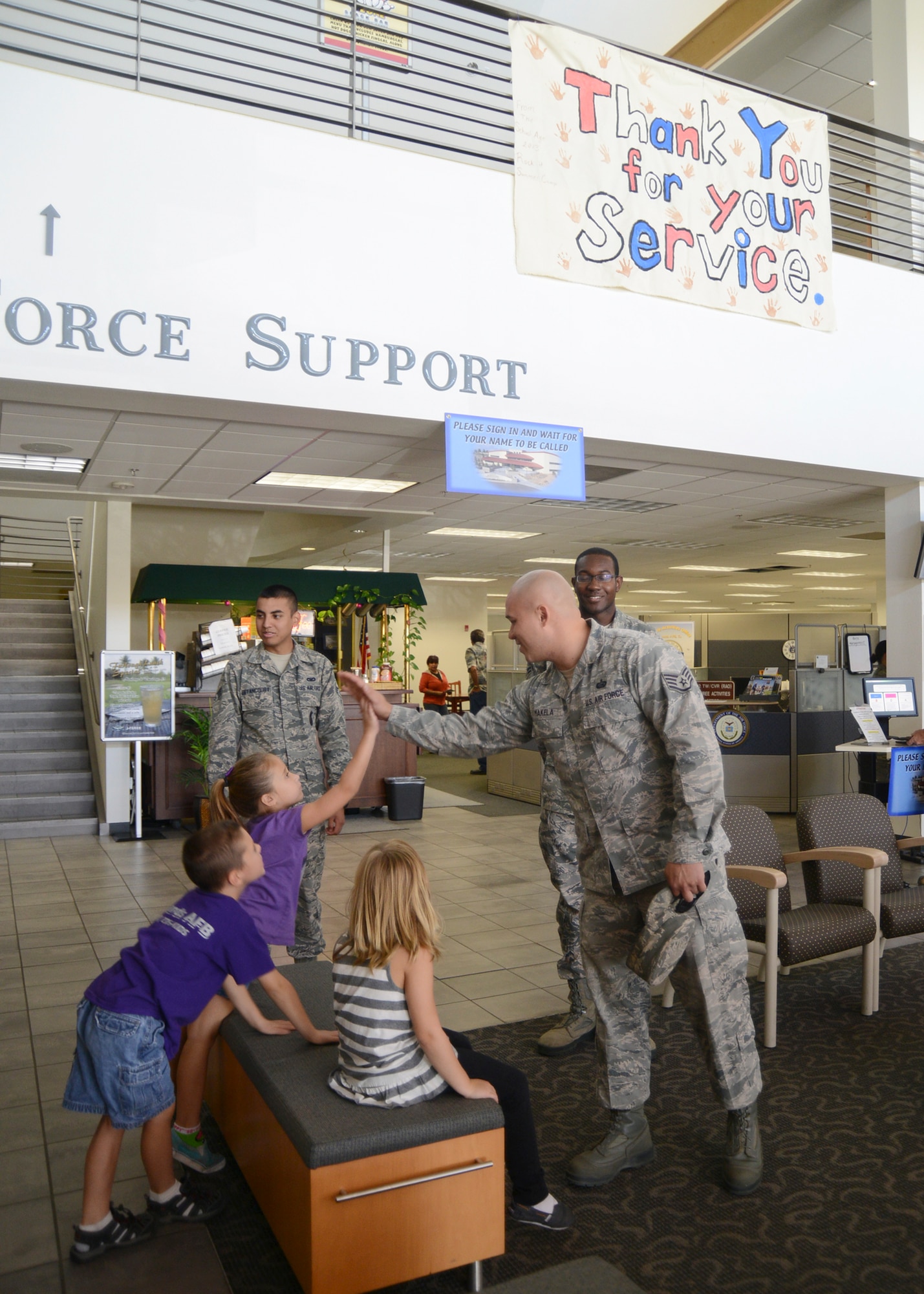 Staff Sgt. Michael Makela, 412th Force Support Squadron, high five’s one of the children from the School Age Annex that donated a banner thanking Airmen for their service, which was hung in Bldg. 3000 Aug. 6. (U.S. Air Force photo by Rebecca Amber) 
