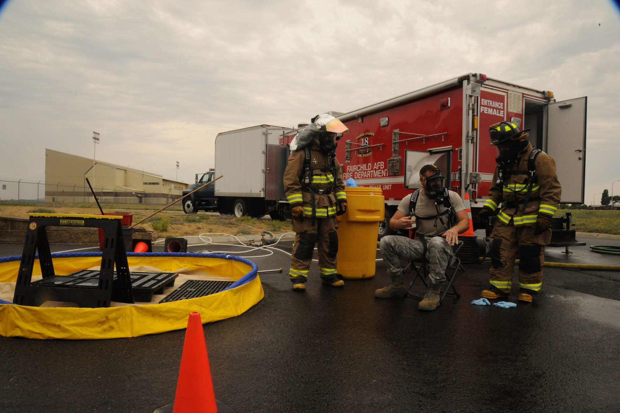 Senior Airman Adam Wriglesworth, 92nd Civil Engineer Squadron readiness journeyman, discusses the completed Chemical, Biological, Radiological and Nuclear Defense exercise with firefighters at Fairchild Air Force Base, Wash., Aug. 1, 2013.  Emergency responders increased their capabilities by learning and conducting CBRN-focused vulnerability assessments, participating in first responder training, applying countermeasure and defense applications, utilizing appropriate personal protective equipment and demonstrating proficiency with CBRN identification and analytical equipment and methodologies.  (U.S. Air Force photo by Airman 1st Class Sam Fogleman/Released)      