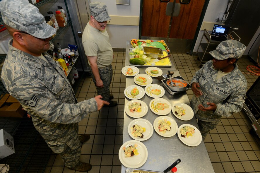 Participants of an Iron Chef competition look over their food dishes at the Chief Master Sgt. Emerson Williams Dining Facility, Shaw Air Force Base, S.C., July 30, 2013. The competition was judged on two dishes prepared with the secret ingredient of papaya. (U.S. Air Force photo by Airman 1st Class Jensen Stidham/Released)