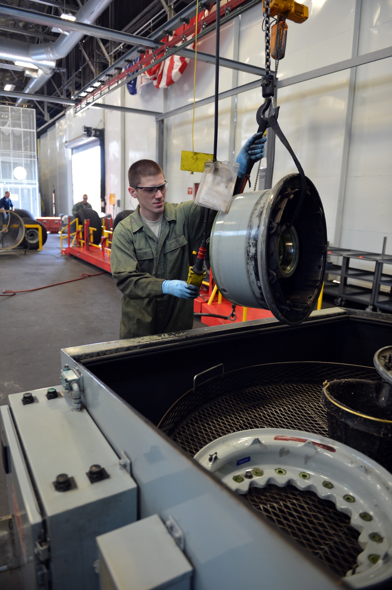 Staff Sgt. Christopher Hirsch, 62nd Maintenance Squadron aerospace maintenance journeyman, lowers a C-17 Globemaster III aircraft wheel assembly, which is a two-part design that weighs approximately 80-pounds, into the wheel washing machine Aug. 1, 2013 at Joint Base Lewis-McChord, Wash. The solvent in the washing machine breaks down the dirt and grime making it easier for technicians to scrub away the debris. (U.S. Air Force photo/Staff Sgt. Jason Truskowski)