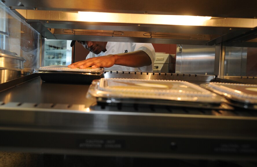 Senior Airman Rick Carroll, 28th Force Support Squadron food service technician, places meals on the hot food line at the new food kiosk in the 34th Bomb Squadron at Ellsworth Air Force Base, S.D., July 24, 2013. The meals are prepared in to-go containers to accommodate airmen working on the fast-paced flight line. The new food kiosk will be open for breakfast, lunch and dinner, Monday through Friday and additionally for midnight meals, Sunday through Thursday. (U.S. Air Force photo by Airman 1st Class Rebecca Imwalle/Released)