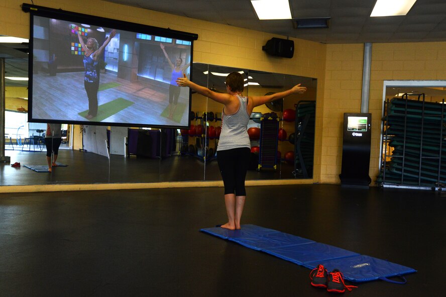 Addison Johnson, wife of Airman 1st Class Jensen Stidham, watches a “Fitness on Request” video while practicing yoga at the fitness center, Shaw Air Force Base S.C., Aug. 1, 2013.  The new program at the fitness center “Fitness on Request” offers a unique twist on a personal trainer. (U.S. Air Force photo by Airman 1st Class Jensen Stidham/Released) 