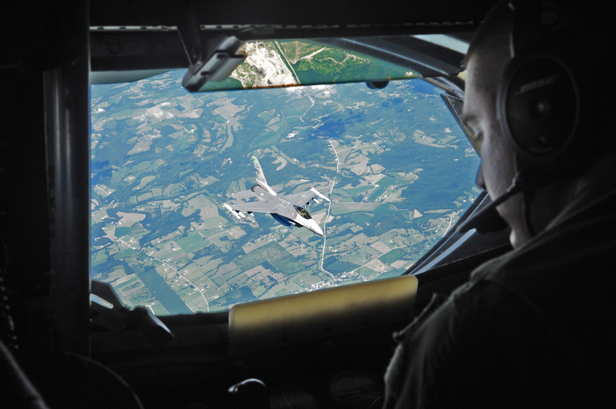 Senior Airman Sam Bradford, 906th Air Refueling Squadron boom operator, watches an F-16 Fighter Falcons from the 180th Fighter Wing fly away after being refueled by a U.S. KC-135R Stratotanker July 25, 2013.  The Stratotanker flew from Scott AFB to Ohio airspace for a local training sortie.  (U.S. Air Force photo by Staff Sgt. Maria Bowman)