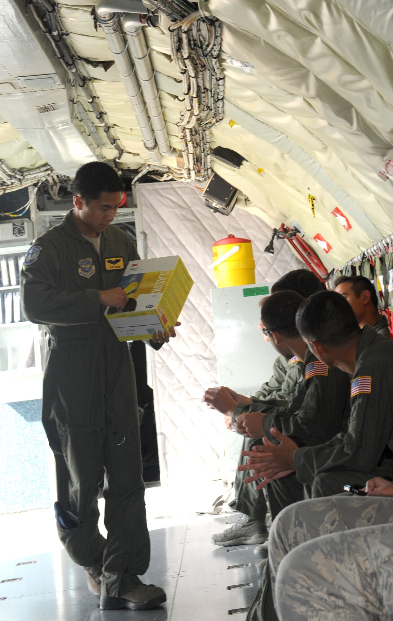 1st Lt. James Quon, passenger monitor, hands out ear plugs on the U.S. KC-135R Stratotanker prior to take-off July 25, 2013.  The personal protective equipment helps protect passenger’s hearing against the loud noises during flight.  The aircraft was heading out to refuel two F-16 Fighter Falcons from the 180th Fighter Wing as part of a local training sortie.   (U.S. Air Force photo by Staff Sgt. Maria Bowman)