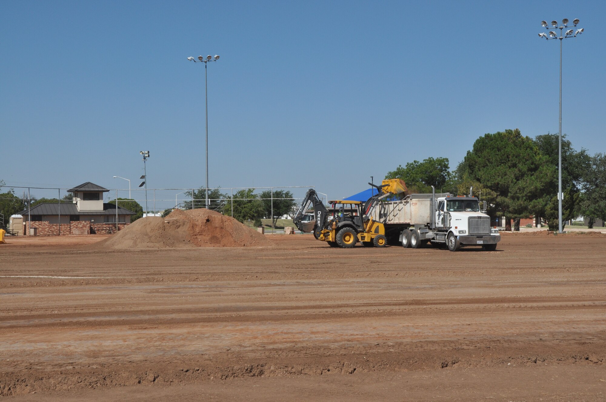 GOODFELLOW AIR FORCE BASE, Texas – A backhoe dumps excess dirt into the bed of a truck at a softball field here, Aug. 6. The field is under construction to replace the grass with AstroTurf in a Health and Wellness initiative. (U.S. Air Force photo/ Airman 1st class Joshua Edwards)