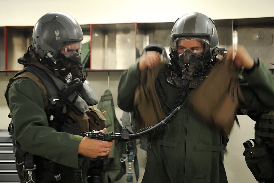 Capt. Robert Carpenter and 1st Lt. Cale Lamoreux, pilots with the 25th Fighter Squadron, help each other don their Aircrew Eye and Respiratory Protection equipment during Operational Readiness Exercise Beverly Midnight 13-03, at Osan Air Base, Republic of Korea, Aug. 5, 2013. When AERP equipment is worn, the pilot must be helped to dress and be systematically "undressed" by AFE technicians. The wing executes military operations to beddown, maintain and employ follow-on forces for the combined arms base that includes three major flying tenants and large multiservice fighting units. (U.S. Air Force photo/Staff Sgt. Sara Csurilla)