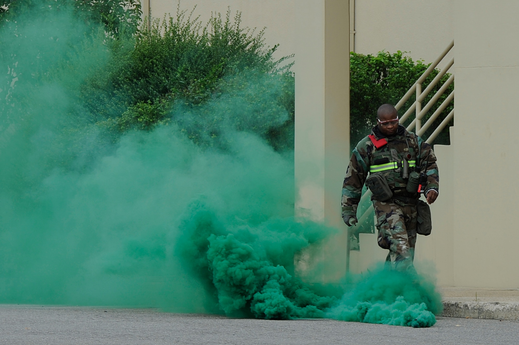 KUNSAN AIR BASE, Republic of Korea -- Master Sgt. Sharome Rudolph, 8th Fighter Wing weapons safety and exercise evaluation team member, sets up smoke grenades outside a building during exercise Beverly Midnight 13-3, Aug. 6, 2013. Training aids like smoke and ground-burst simulators add a sense of realism during wartime scenarios. (U.S. Air Force photo by Staff Sgt. Tong Duong/Released)