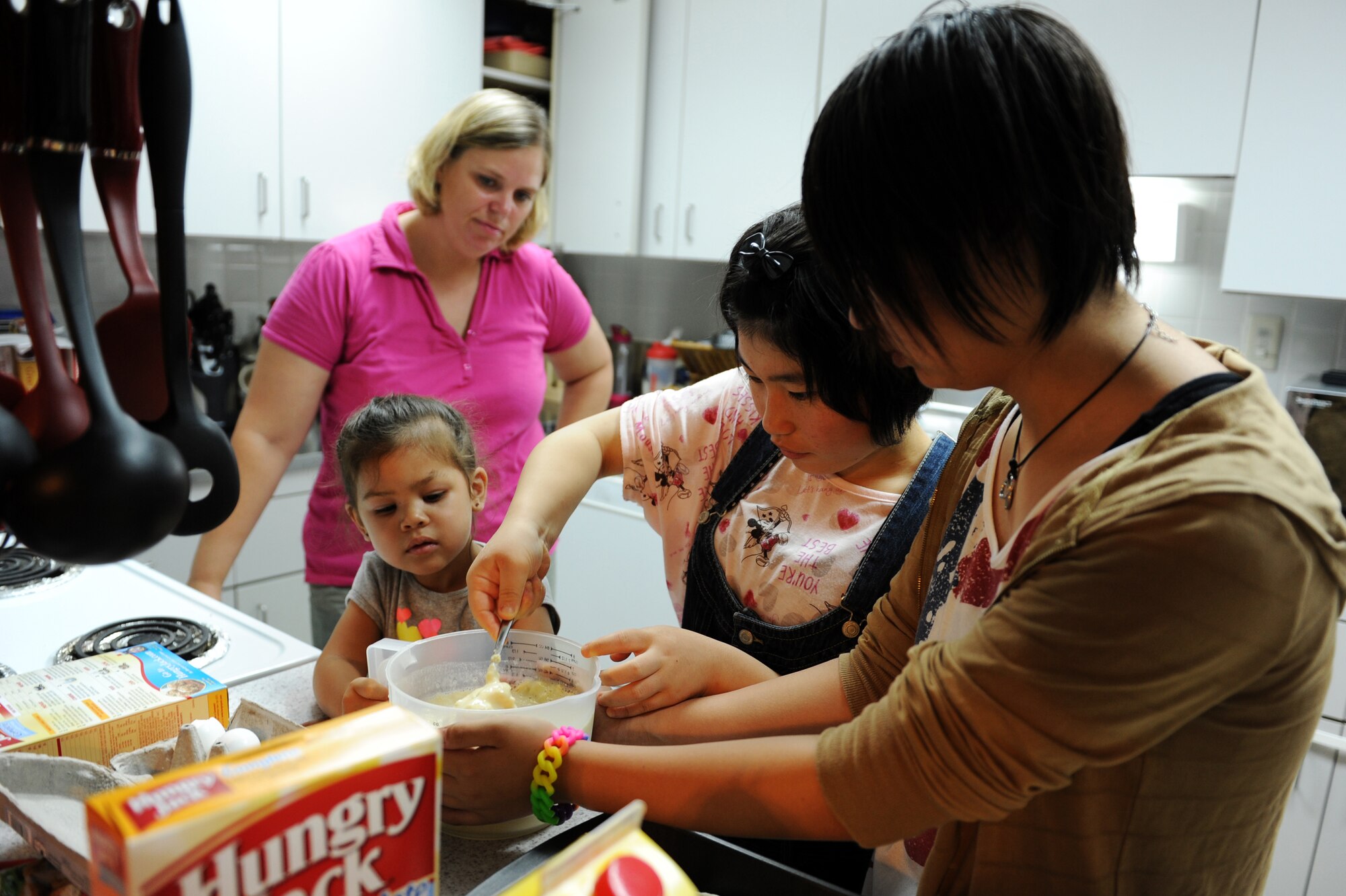 From left: U.S. Air Force Tech. Sgt. Marie Brown, 35th Fighter Wing Public Affairs NCO in charge of U.S. media relations, her daughter, Amane Nakamura and Nanase Abe, students from Tanohata Junior High School, cook breakfast together during a weekend Homestay event at Misawa Air Base, Japan, Aug. 4, 2013. Along with showing continued national support following the earthquake and tsunami disaster in 2011, the Homestay program, sponsored by the Misawa International Club, allows local national students to experience American culture with a weekend stay with families at Misawa Air Base. (U.S. Air Force photo by Senior Airman Kia Atkins)