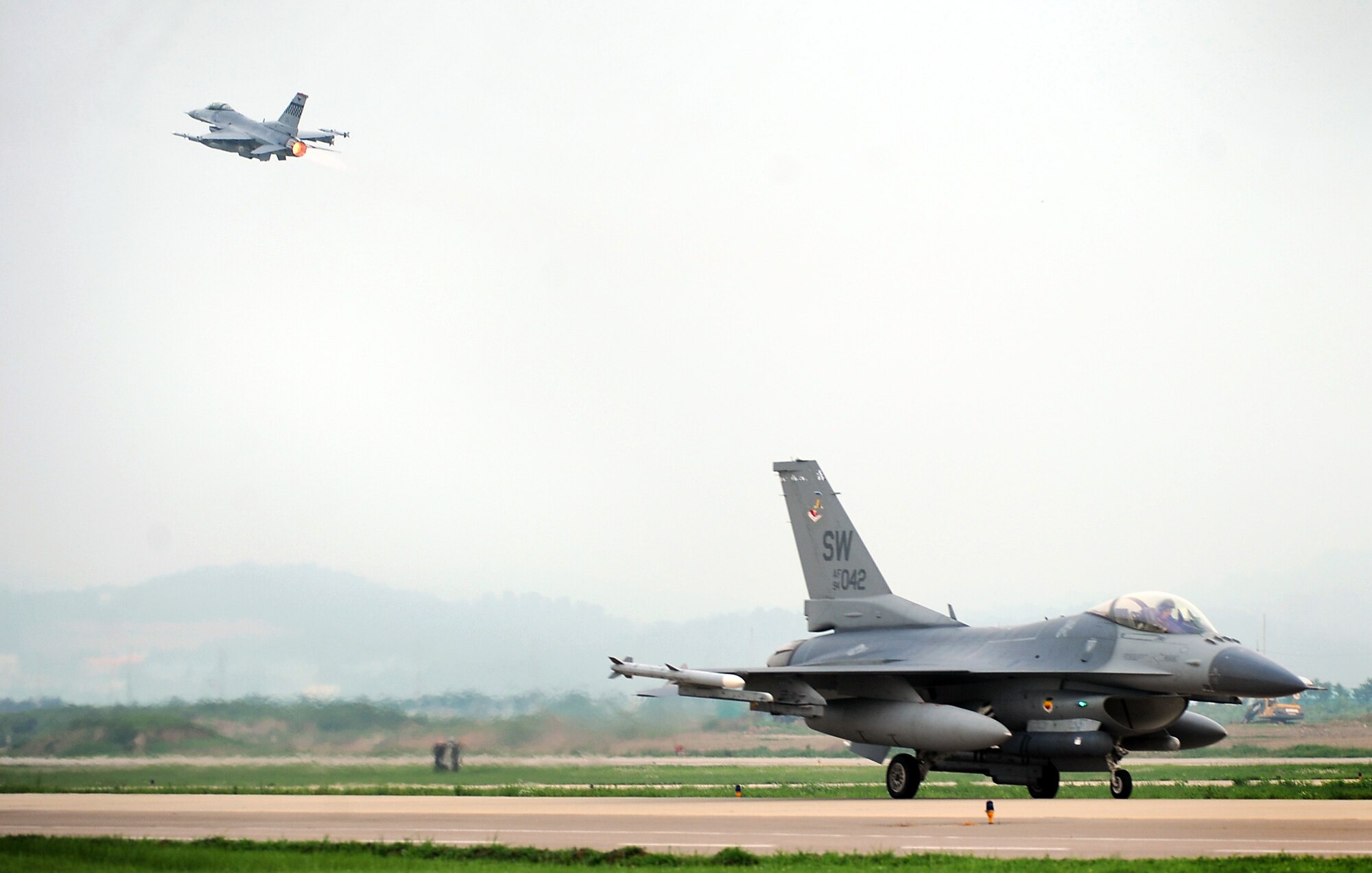 An F-16 Fighting Falcon from the 36th Fighter Squadron takes off for the first combat sortie of Operational Readiness Exercise Beverly Midnight 13-03, as an F-16 Fighting Falcon from the 55th Expeditionary Fighter Squadron taxis for takeoff at Osan Air Base, Republic of Korea, Aug. 6, 2013. Osan Airmen are in the fourth simulated wartime contingency exercise executed in 2013 that will test the base's ability to defend and execute the mission in a heightened state of readiness. (U.S. Air Force photo/Staff Sgt. Sara Csurilla)