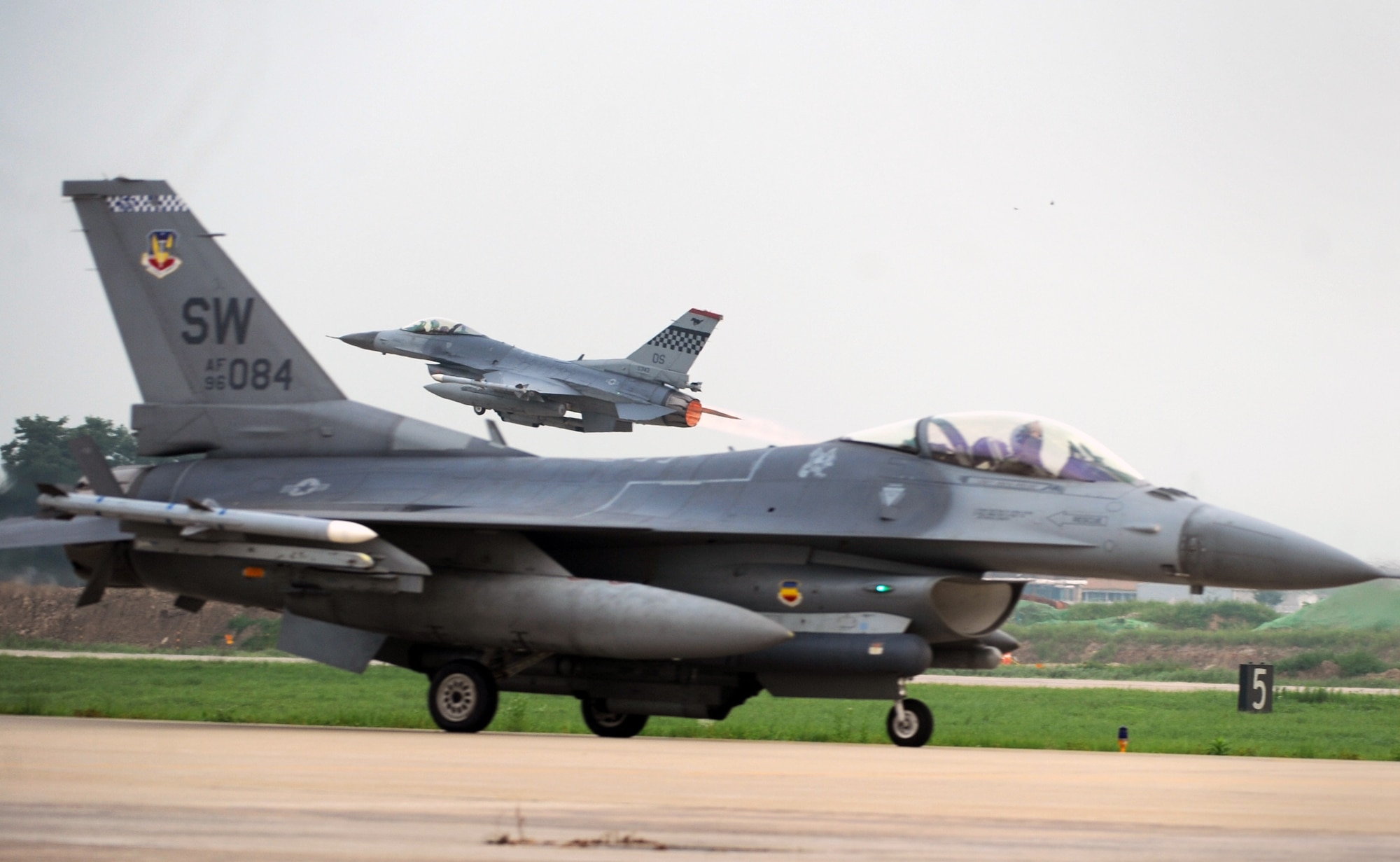 An F-16 Fighting Falcon from the 36th Fighter Squadron takes off for the first combat sortie of Operational Readiness Exercise Beverly Midnight 13-03, as an F-16 Fighting Falcon from the 55th Expeditionary Fighter Squadron taxis for takeoff at Osan Air Base, Republic of Korea, Aug. 6, 2013. During the week, Osan Airmen will be tested on their ability to utilize their chemical, biological, radiological and nuclear training, as well as administer self-aid and buddy-care during contingency operations. (U.S. Air Force photo/Staff Sgt. Sara Csurilla)