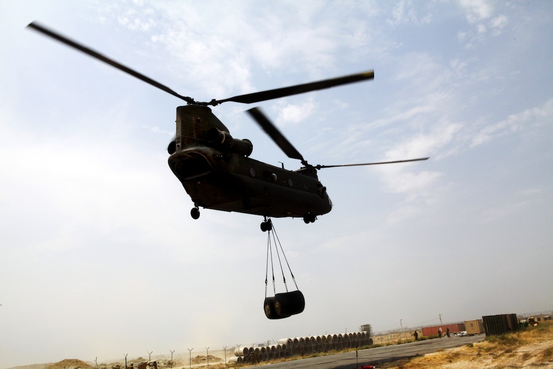 A CH-47 Chinook helicopter prepares to unload two 500-gallon fuel blivets during a sling-load training exercise, Bagram Airfield, Afghanistan, July 30, 2013.