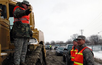 Spc. Joshua Klundt, of the 817th Engineer Company (Sappers), pulls one end of a collapsible barrier device called a HESCO March 24 in Fargo, N.D. The sections of HESCO are being linked together and filled with sand to create a flood barrier from the rising waters of the Red River.