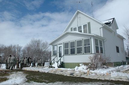 Quick Reaction Force members wait near Mike Schmidt's home for more sandbags after using their first shipment to form the base of a temporary dike on April 1, 2009.