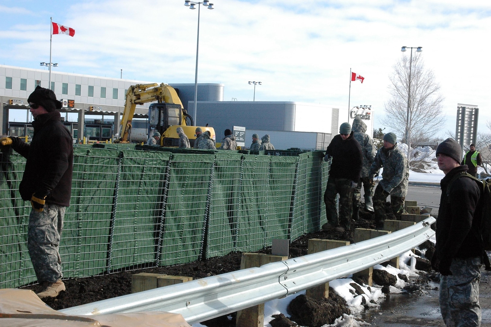 Soldiers of the 815th Engineer Company carefully install a HESCO barrier near the U.S.-Canadian border. The barrier will reinforce the dike system already in place by adding four feet, which will bring it from 53 feet to 57 feet.