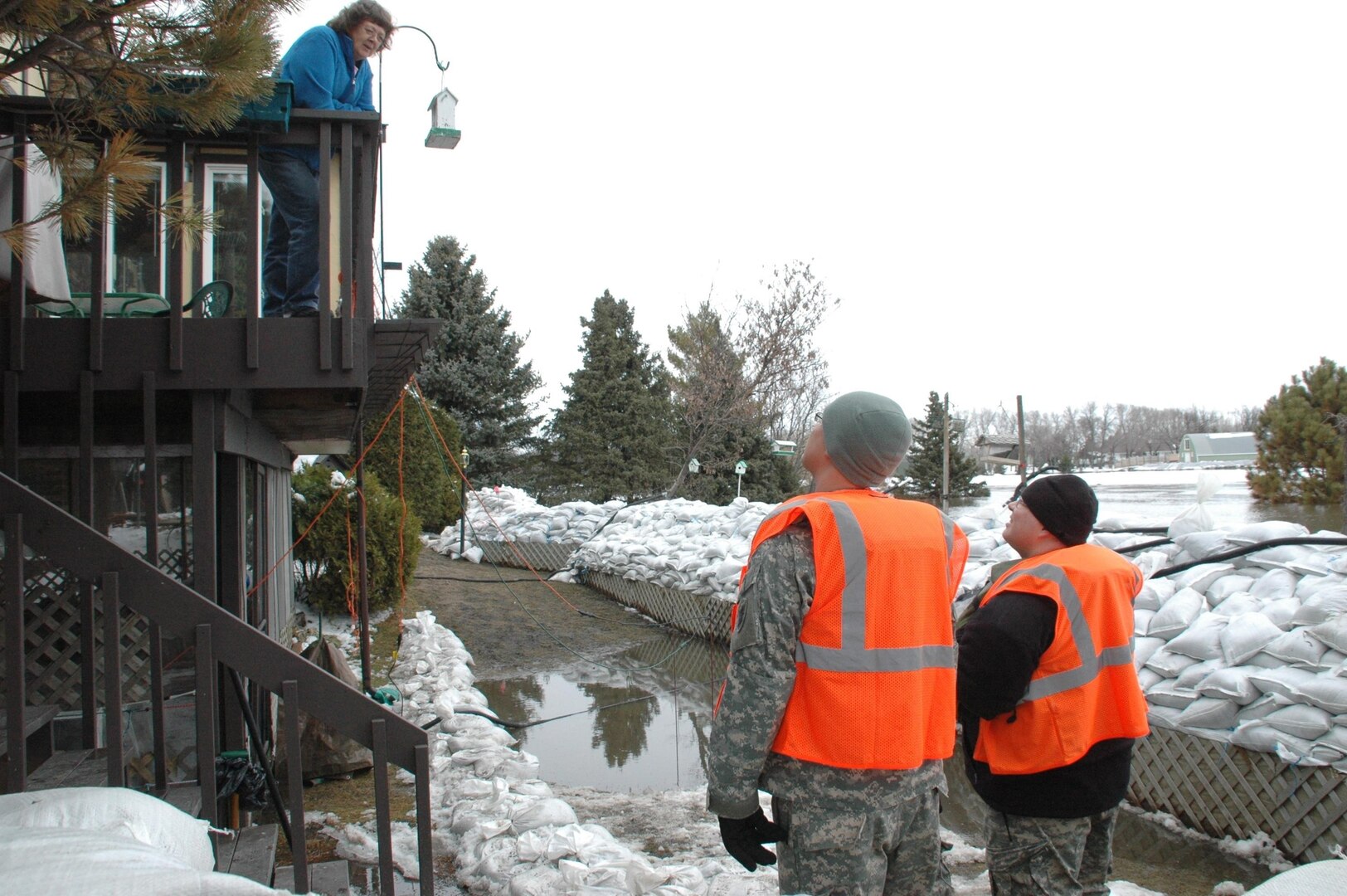 Spc. Nathan T. Blair and Spc. John P. Finck, North Dakota Soldiers with the 1-188th Air Defense Artillery, discuss flooding with homeowner Eunice Kuhn. Kuhn lives in the Burke Addition southeast of Grand Forks.