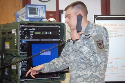 Sgt. Chris A. Olson, with the South Dakota National Guard's Joint Force Headquarters, operates the communication handset on the Joint Incident Site Communications Capability (JISCC) system. The system allows Soldiers and Airmen to communicate with emergency responders on the ground fighting the flood.