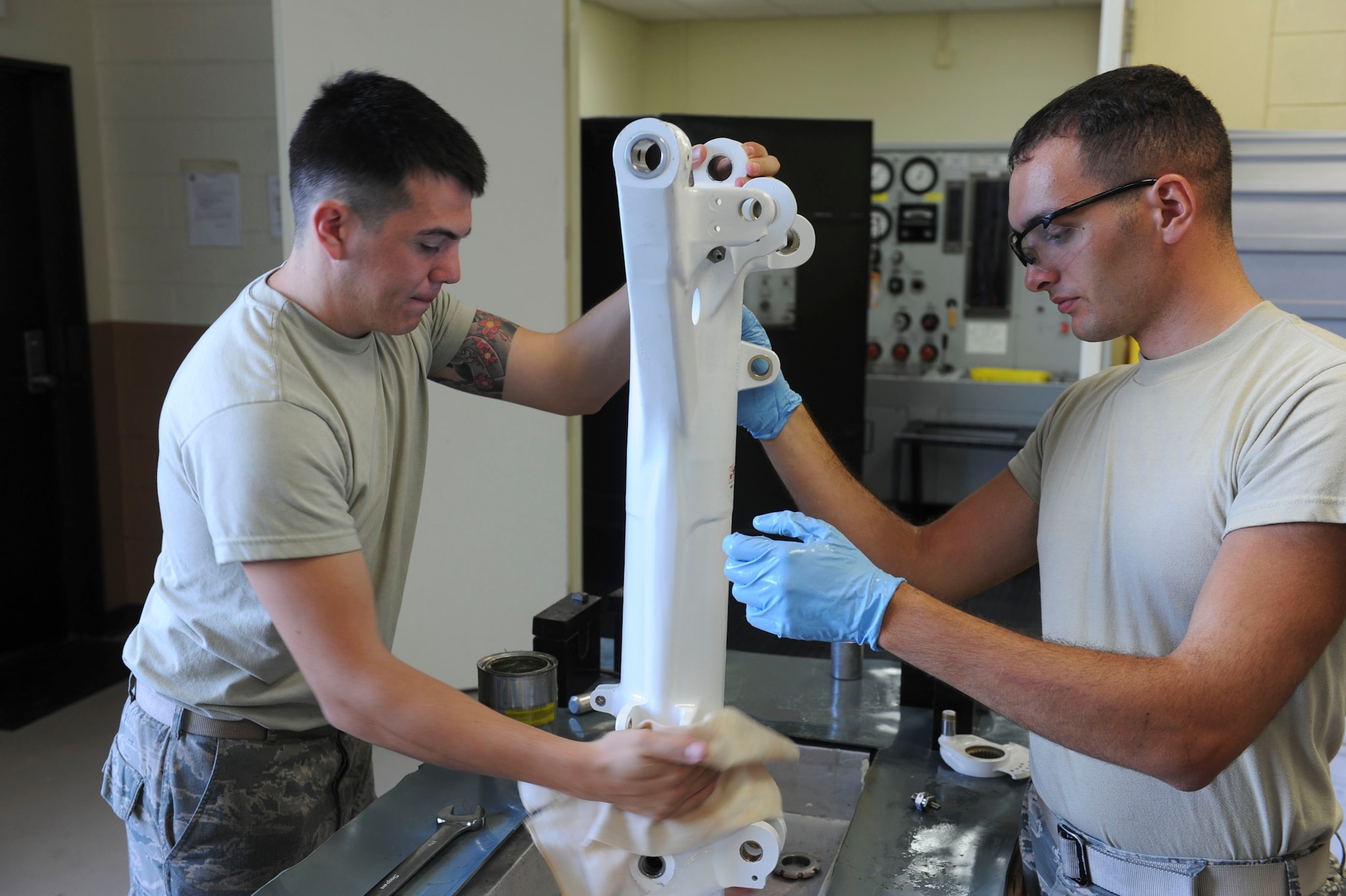 U.S. Air Force Senior Airman Stefan LaVe, 18th Component Maintenance Squadron hydraulics apprentice, wipes excess hydraulic fluid off an F-15 Eagle aircraft nose landing gear strut on Kadena Air Base, Japan, Aug. 6, 2013. Airmen from the hydraulic backshop wipe off the gear in preparation for their inspection of the part. (U.S. Air Force photo by Airman 1st Class Justin Veazie/Released)