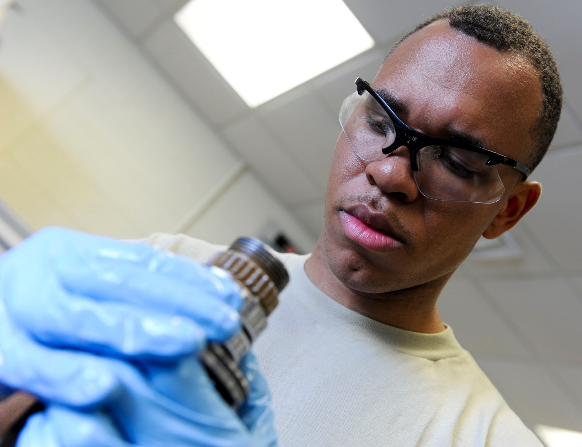 U.S. Air Force Airman 1st Class Tavon Harris, 18th Component Maintenance Squadron hydraulics apprentice, inspects the seals on an F-15 Eagle aircraft nose landing gear strut for cracks on Kadena Air Base, Japan, Aug. 6, 2013. The 18th CMS provides maintenance on electronics for propulsion, avionics and airframe accessory sub-systems for all assigned aircraft on Kadena and maintains the only four-bay engine test facility in Pacific Air Forces. (U.S. Air Force photo by Airman 1st Class Justin Veazie/Released)