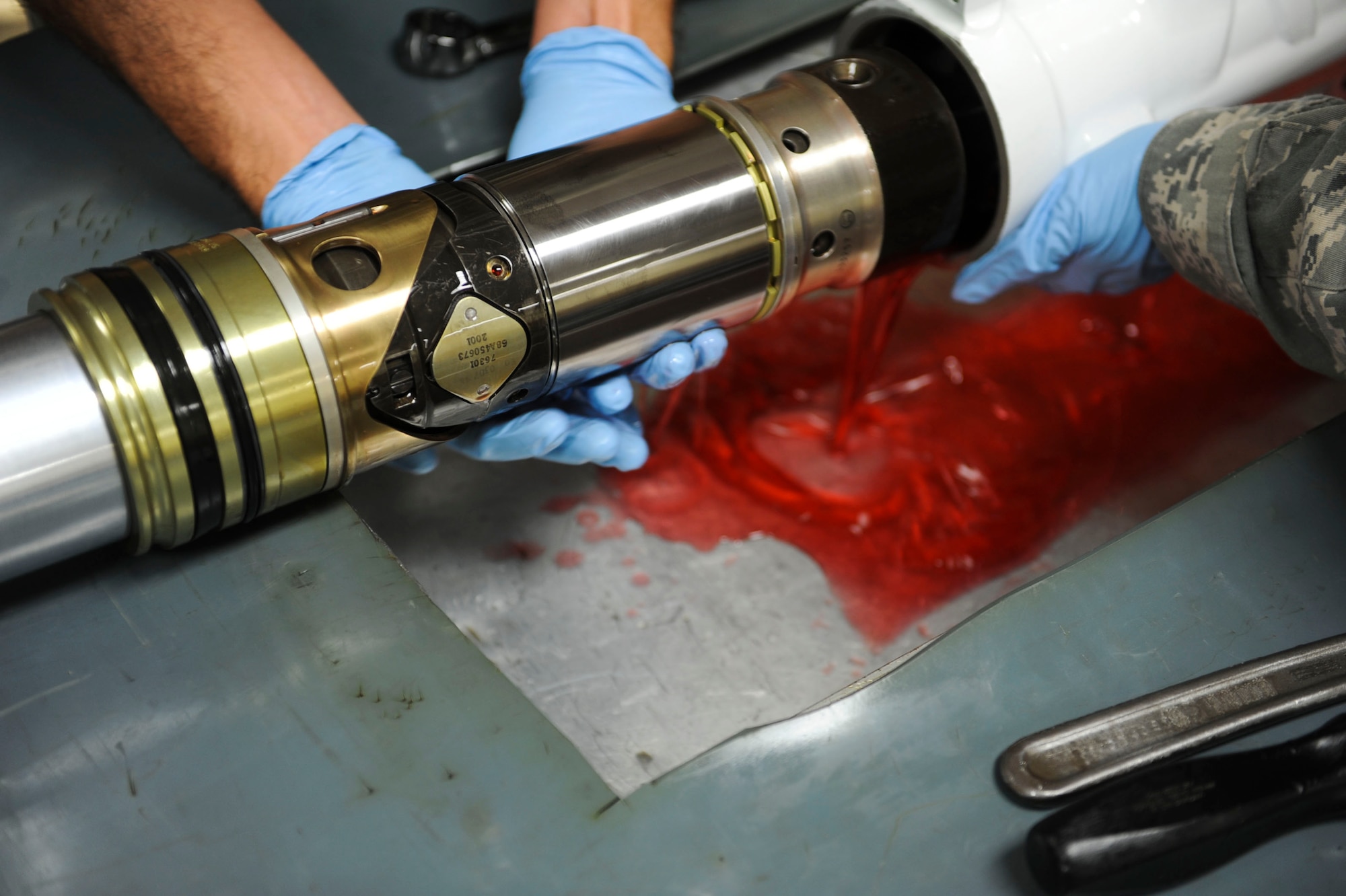U.S. Air Force Airman 1st Class Michael Whitley, 18th Component Maintenance Squadron hydraulics apprentice, drains the hydraulic fluid out of an F-15 Eagle aircraft nose landing gear strut on Kadena Air Base, Japan, Aug. 6, 2013. Whitley drains the hydraulic fluid during a routine inspection, to ensure it meets all mission requirements. (U.S. Air Force photo by Airman 1st Class Justin Veazie/Released)