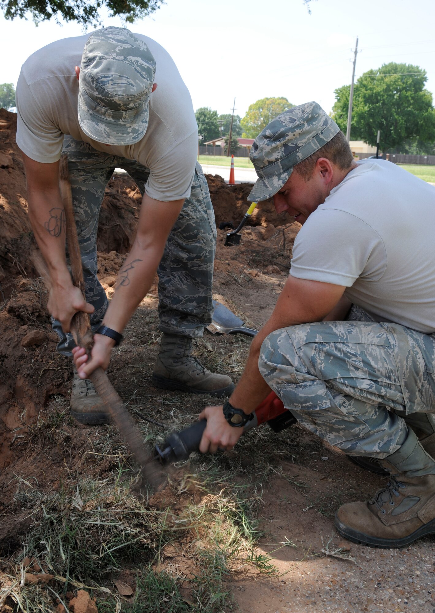 Senior Airman Michael Bustamante, left, and Airman 1st Class Jefferson Bowler, 2nd Civil Engineer Squadron Water and Fuels Systems Maintenance, cut roots on Barksdale Air Force Base, La., Aug. 7, 2013. The roots were cut to make room for a fire hydrant. (U.S. Air Force photo/Airman 1st Class Andrew Moua)