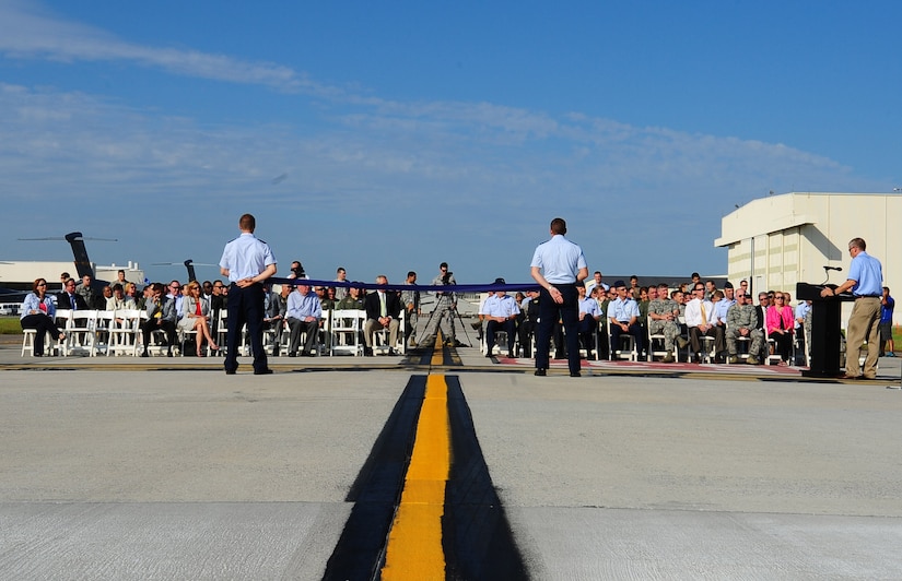 People await the ribbon cutting during the opening of new Joint Base Charleston Runway Aug. 7, 2013, at JB Charleston – Air Base, S.C. The construction project began last summer to replace the aging main runway, which was over 50 years old.  The original runway was safely kept in service by routine inspections and conducting spot repairs.  However, the runway was well beyond its originally programmed service life and was in need of replacement. The newly constructed runway is 9,000 feet long and 150-feet wide and 18-inches thick at a cost approximately $40 million. The runways at Joint Base Charleston are part of a dual-use airfield and are shared with the Charleston County Aviation Authority and private industry.  The new runway will be capable of supporting Air Force mission requirements and also serve the local community. In addition, the project added high efficiency LED lighting fixtures, improved infrastructure for navigational aids and an updated aircraft arresting system used to safely recover fighter aircraft experiencing mechanical issues.(U.S. Air Force photo/Airman 1st Class Chacarra Neal)