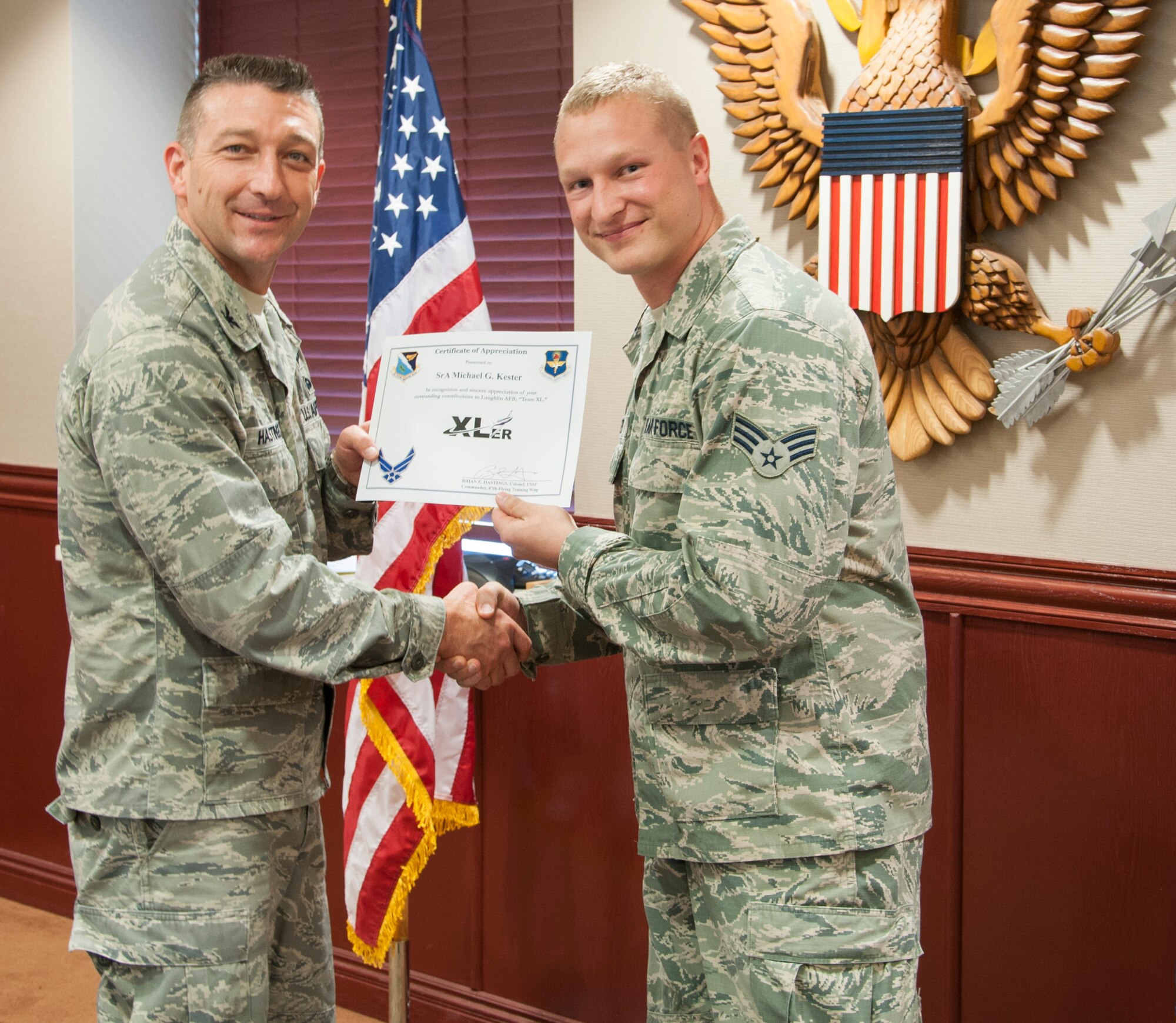 Senior Airman Michael Kester, 47th Communications Squadron Cyber Transport journeyman, poses with Col. Brian Hastings, 47th Flying Training Wing commander, after being presented the XLer of the week award here Aug. 1, 2013. The XLer is a weekly award chosen by wing leadership and given to those who consistently make outstanding contributions to Laughlin and their unit. (U.S. Air Force photo/1st Lt. James Ramirez)