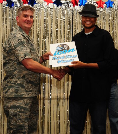 Col. Albert Miller, 437th Airlift Wing vice commander, awards Master Sgt. Toby Housey, 315th Equal Opportunity advisor, third place during the Air Mobility Command Icon Talent Contest Aug. 1, 2013, at Joint Base Charleston - Air Base, S.C. The AMC Icon program is loosely based on the hit TV program, “American Idol.” Housey, from Estill, S.C., performed Maroon 5’s “Sunday Morning.” (U.S. Air Force photo/ Airman 1st Class Chacarra Neal)
