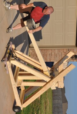 Air Force photos by Mike W. Ray
Master Sgt. Patrick Patterson cocks the catapult he and two other NCOs from the 960th AACS intend to enter in “Viking Fest” this fall. Their machine was constructed from 2x6s and uses three 100-pound exercise bands as its power source. “Considering its mobility, along with the ability to change the launch angle and to fine-tune the tension, we can put ‘warheads on foreheads’ anywhere on the field,” said Patterson, the principal designer of the medieval siege engine.