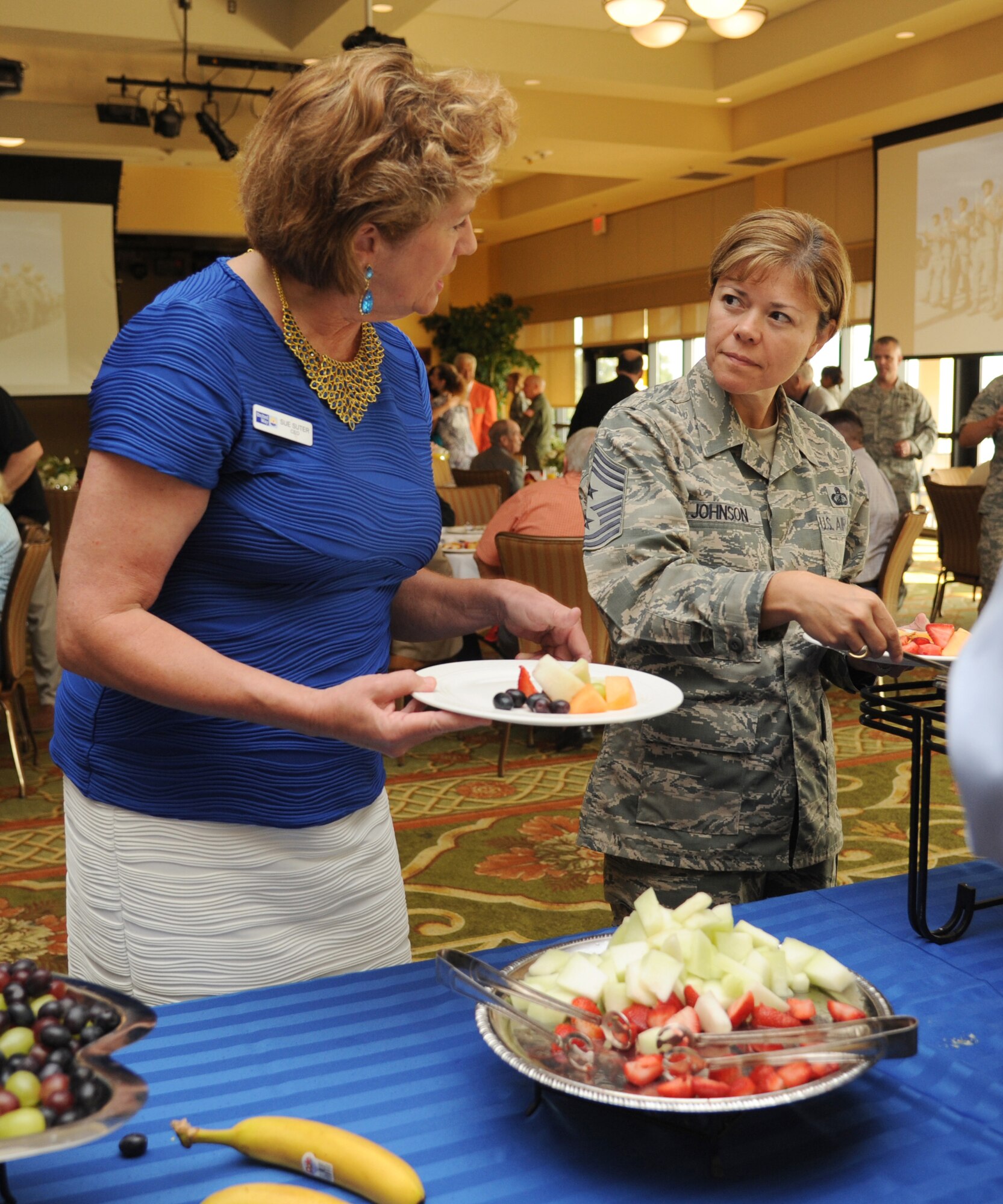 Sue Suter, United Way  chief executive officer,  chats with Chief Master Sgt. Angie Johnson, 81st Training Wing command chief,  in the breakfast buffet line at the Bay Breeze Event Center during the Biloxi Chamber of Commerce Morning Call Aug. 7, 2013, hosted by Keesler Air Force Base, Miss.  (U.S. Air Force photo by Kemberly Groue)