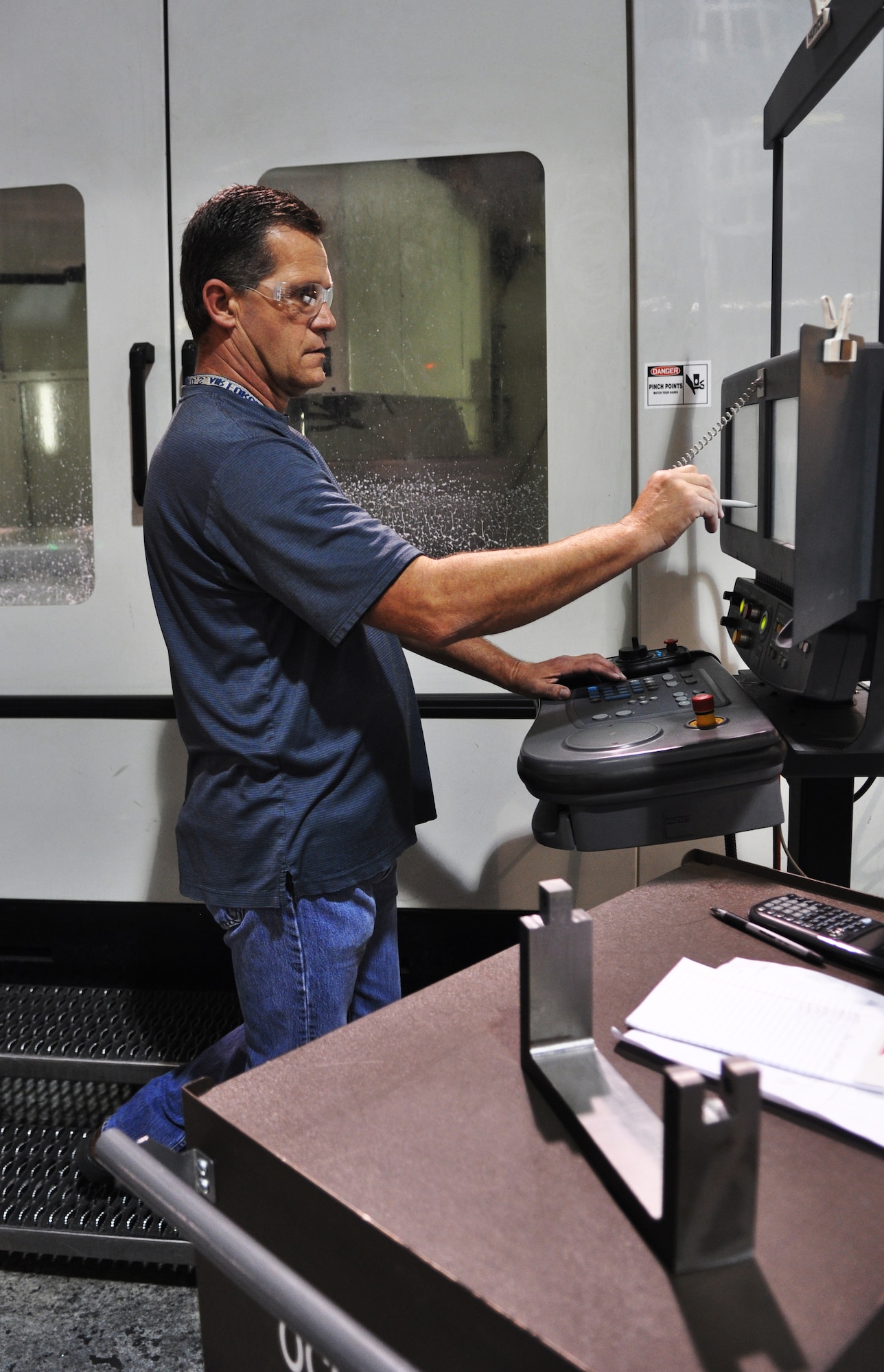 Sheldon Glass, a tool maker with the 76th PMXG Repair and Development unit, programs a CNC machining center to cut out a section of a brace that will be welded to a larger fitting for holding jet engines while they are in the Oklahoma City Air Logistics Complex for maintenance work. (Air Force photo by Micah Garbarino)